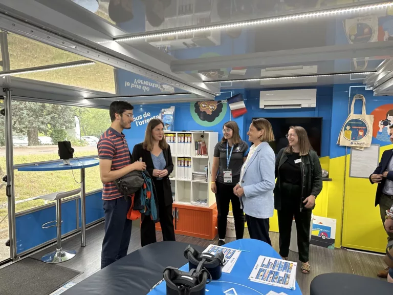 Équipe du bus de l'orientation de la Région Auvergne Rhône Alpes, un événement itinérant favorisant l'orientation chez les élèves de collège et lycée. Tous les membres de l'équipe sont debout à l'intérieur du bus et sont en train de parler ensemble.